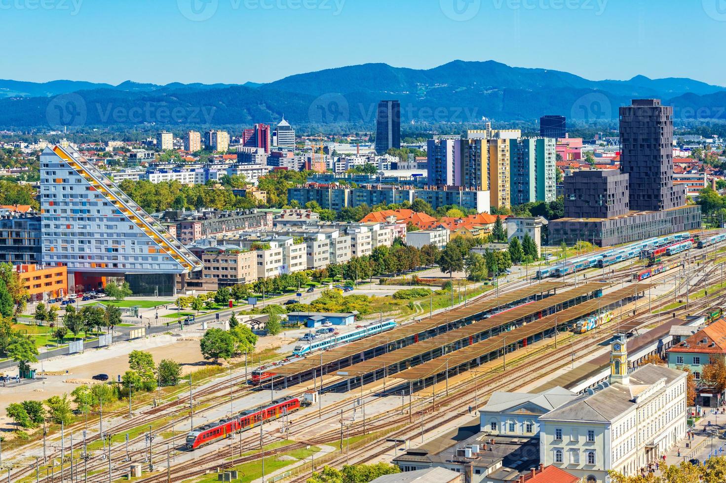 Panorama aéreo de Liubliana con edificios modernos, la estación principal de tren, trenes y hermosas colinas verdes en el fondo, Eslovenia foto