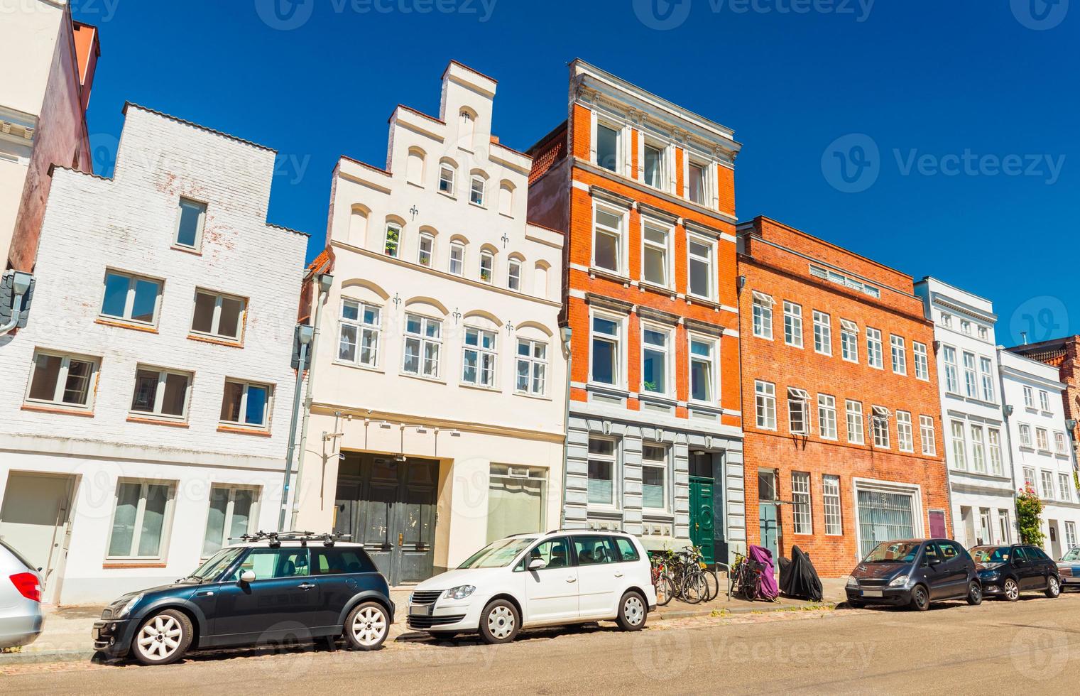una calle de una antigua ciudad alemana. coches modernos aparcados cerca de una hilera de diferentes edificios históricos. Lubeck, Alemania foto