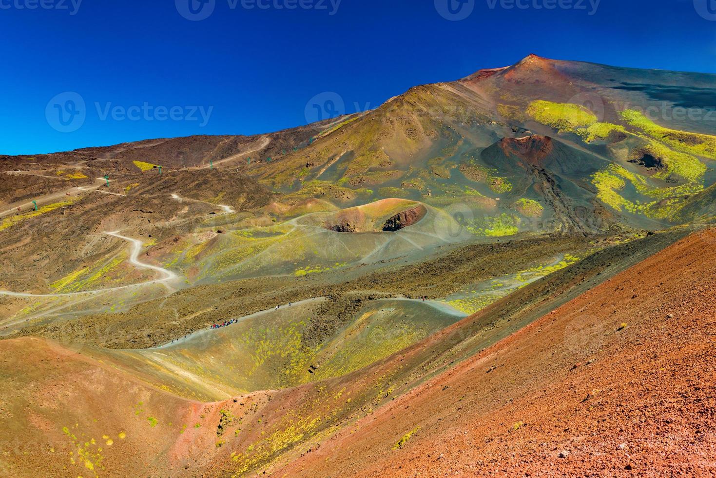 hermoso paisaje del monte etna con numerosos cráteres y un grupo de turistas parados cerca de uno de ellos. sicilia, italia foto