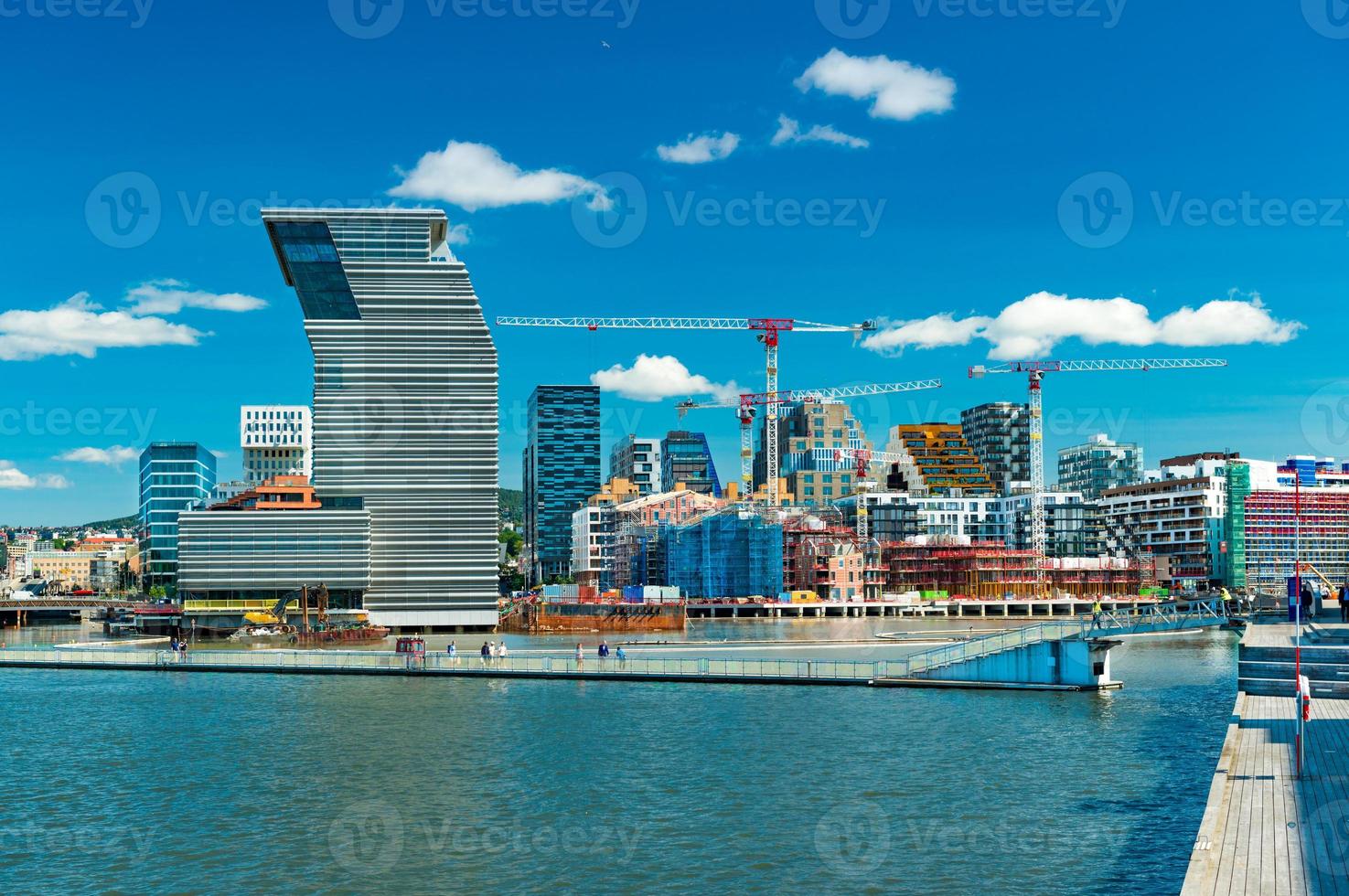Cityscape of Oslo with modern architecture, buildings under construction, tower cranes, harbor and bridge with walking people, Norway photo