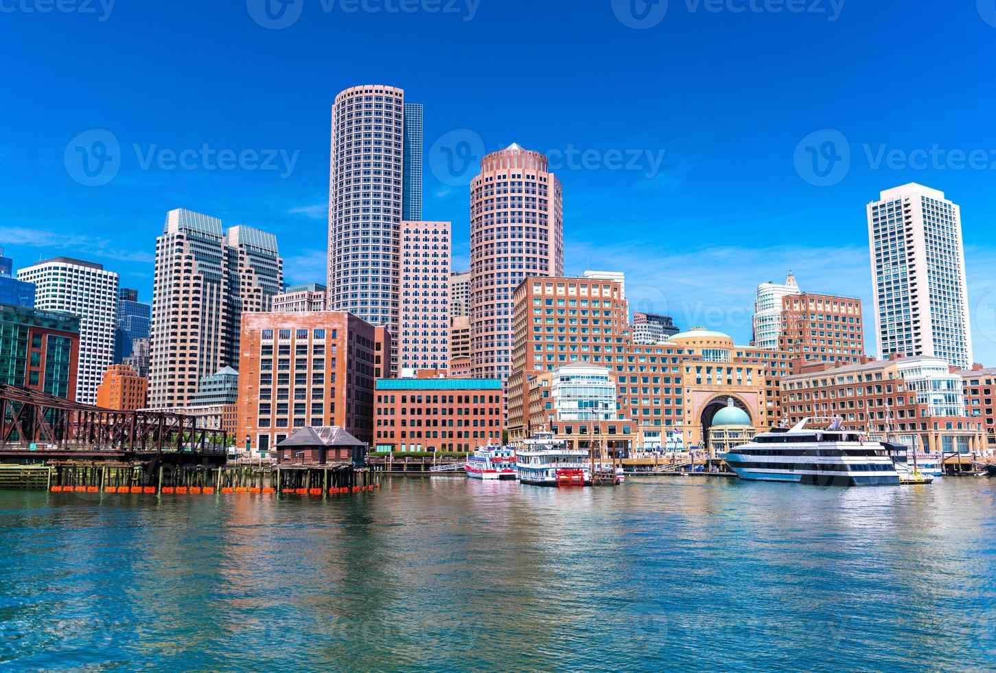 Boston cityscape reflected in water, skyscrapers and office buildings in downtown, view from Boston harbor, Massachusetts, USA photo