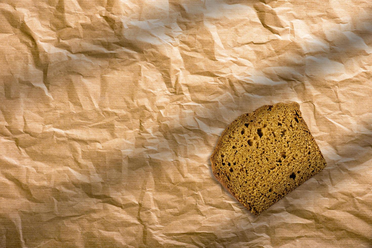 pan de centeno en rodajas sobre un fondo marrón aislado. rebanadas de pan integral envueltas en papel marrón. foto
