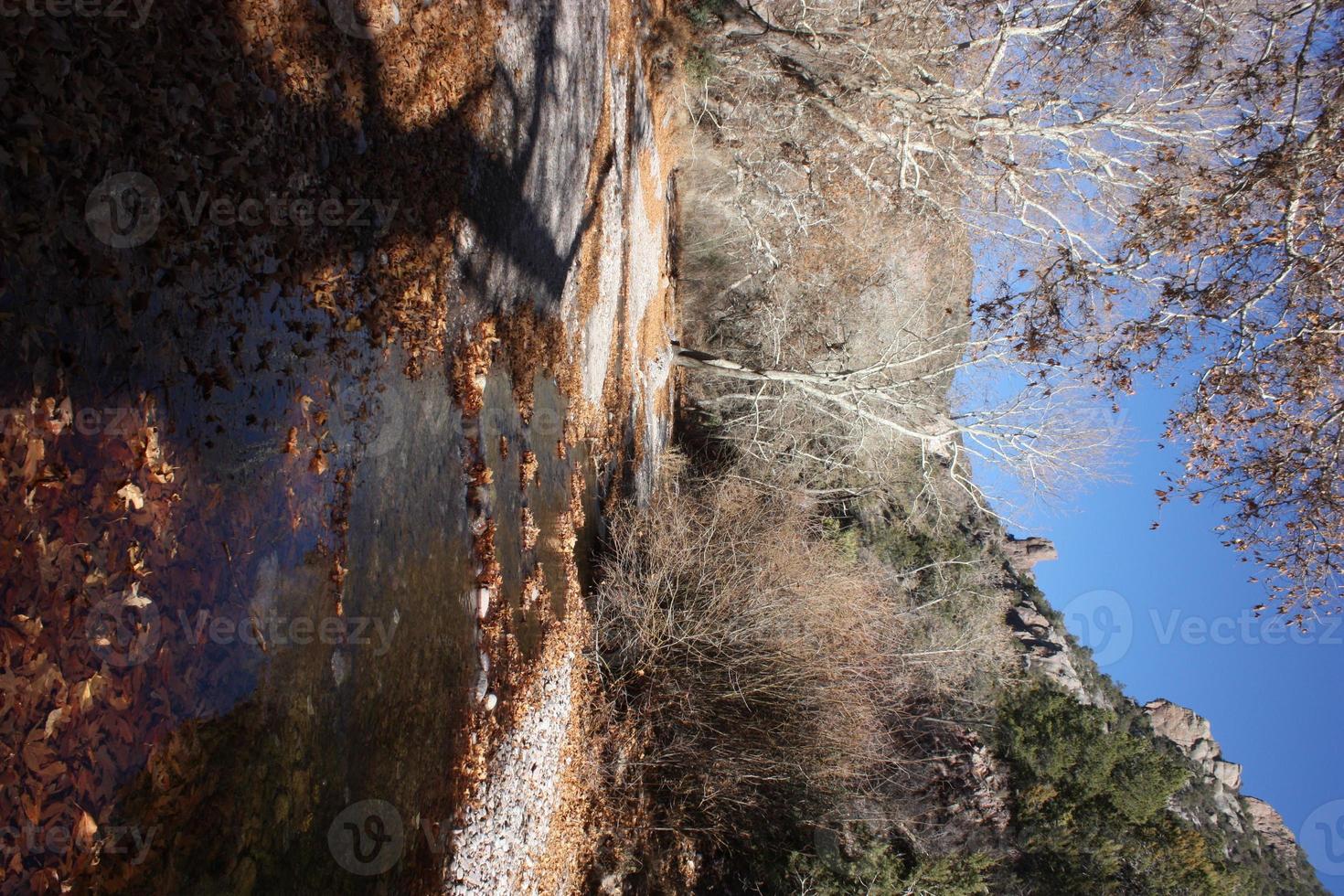 El arroyo de aguas bravas brilla mientras se escurre desde la pasarela en un día fresco con hojas de otoño foto