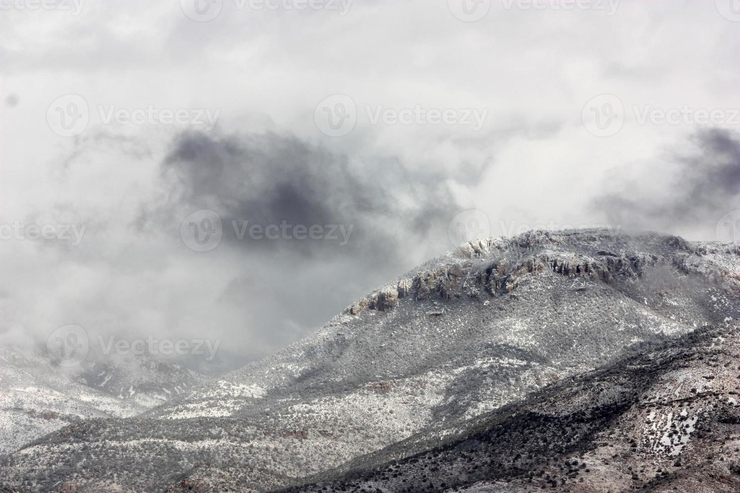 Siniestras nubes de tormenta y nieve que sopla sobre un vasto paisaje montañoso foto