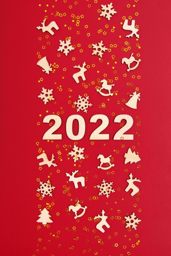 Happy New year 2022 numbers on red background with golden stars and Cristmas wood decorations photo