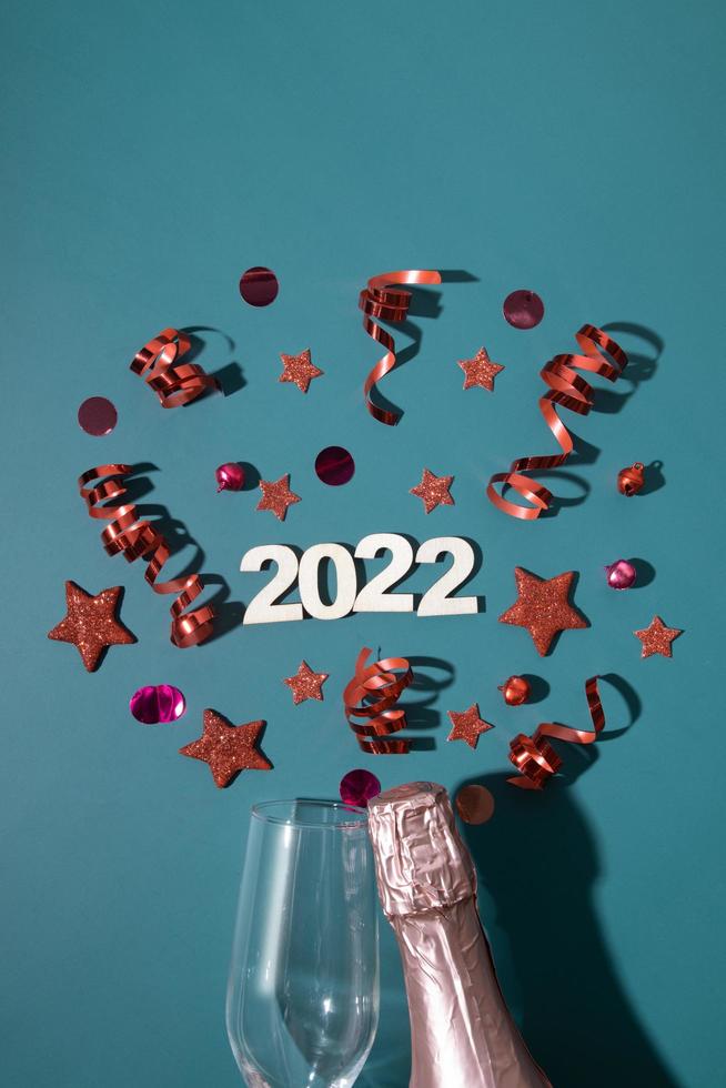 Christmas 2022 new year flat lay with champagne, glass and  stars, streamers on green background photo