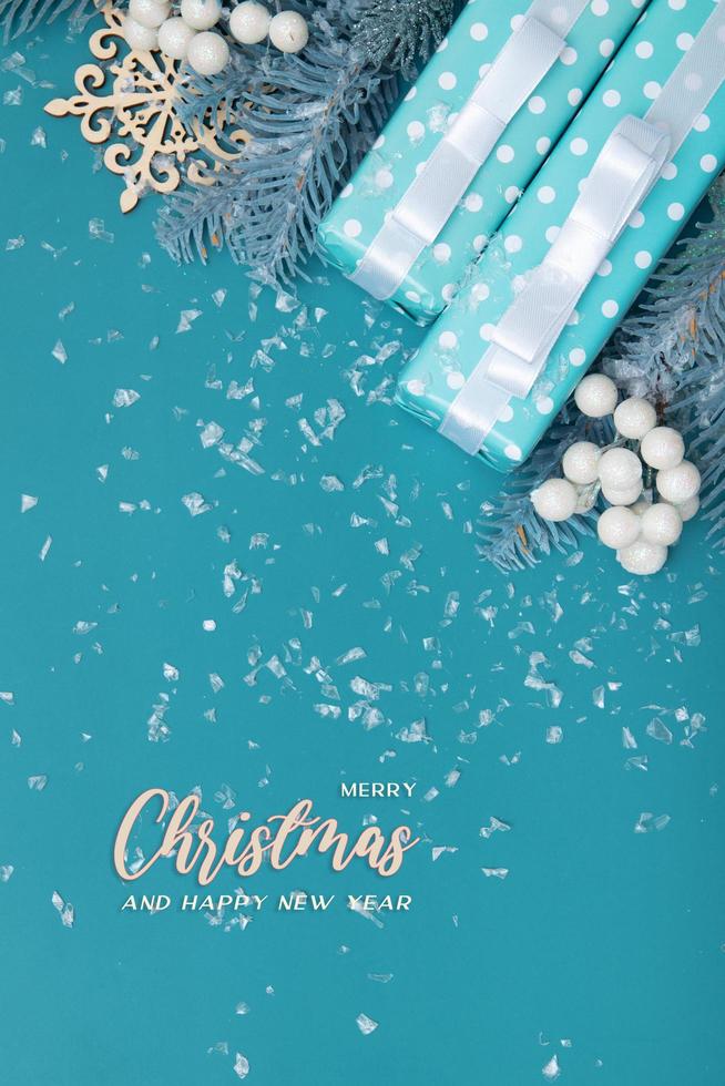 Merry Christmas inscription on a background of gifts and snow flat lay on a turquoise backdrop photo