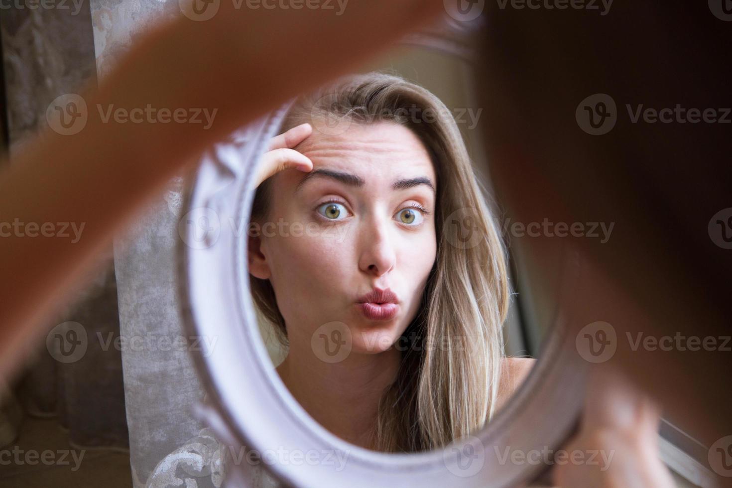 Woman look at the mirror portrait, cute girl touching face an look at the mirror, fashion skin care concept photo