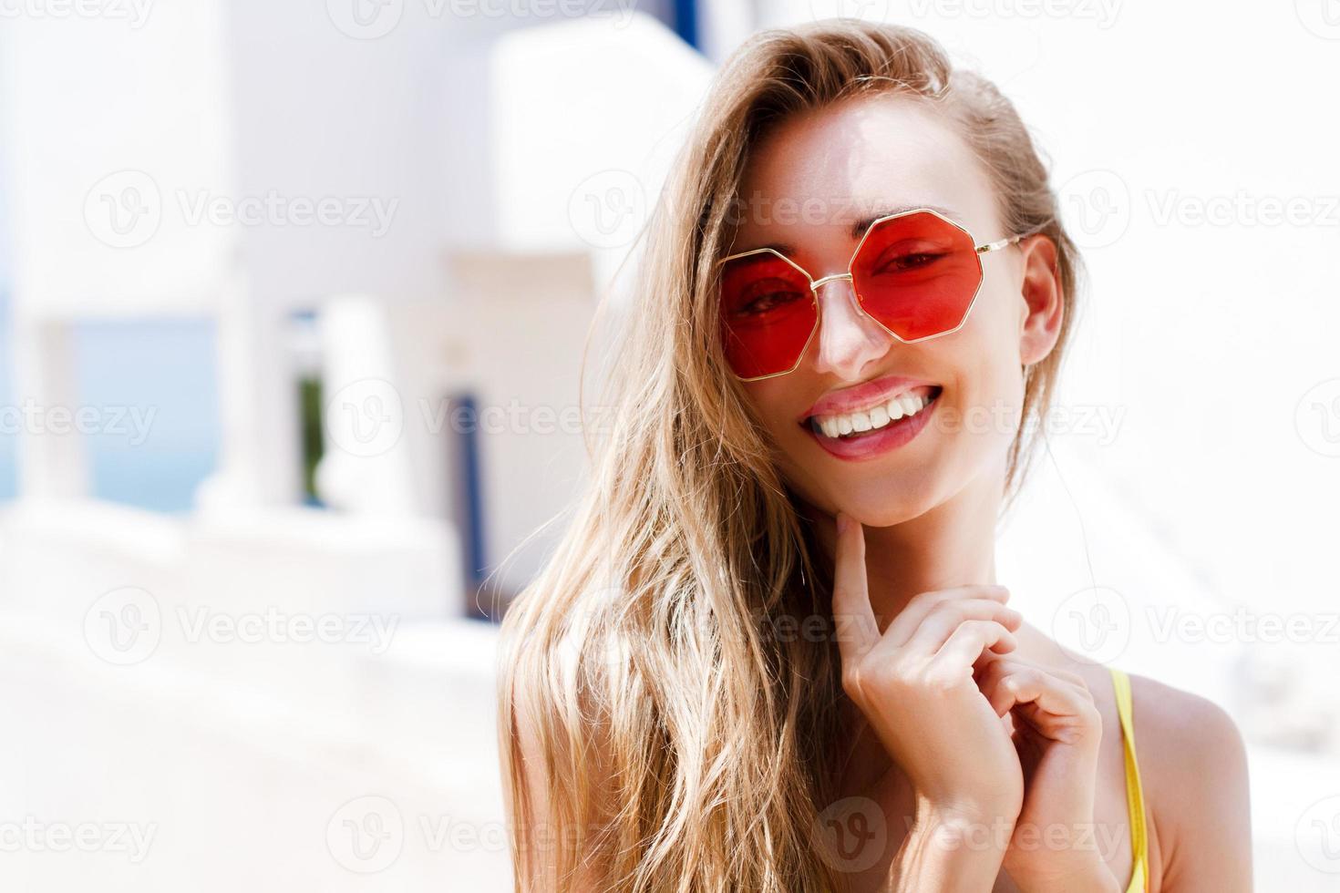 Very beautiful white woman in stylish red sunglasses posing on a sea background of a hotel of the sea and tropics photo