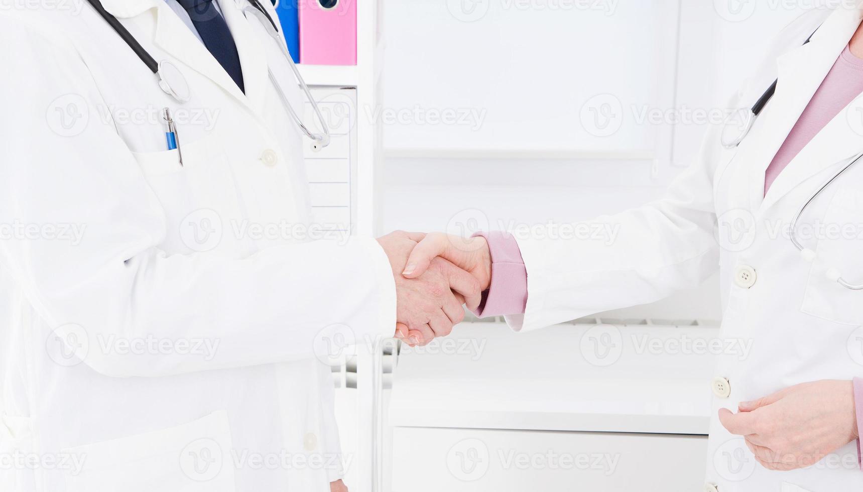 two doctors shake hands in office. Medical insurance. Healthcare concept. Copy space photo