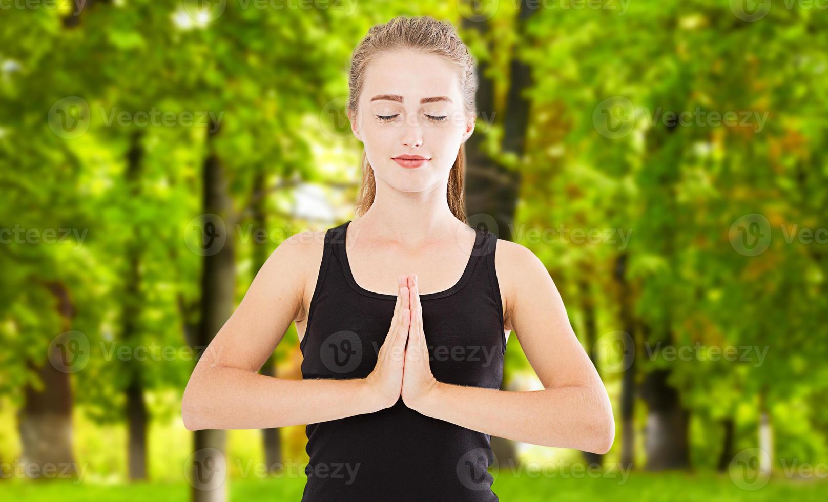 Cerca de las manos de la mujer de yoga en gesto de namaste en el día de verano fuga de luz foto