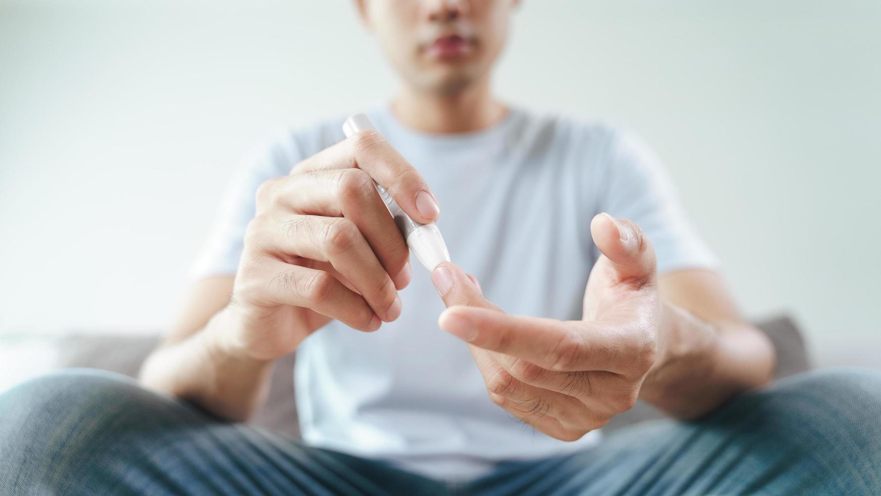 Asian man using lancet on finger for checking blood sugar level by Glucose meter, Healthcare and Medical, diabetes, glycemia concept photo