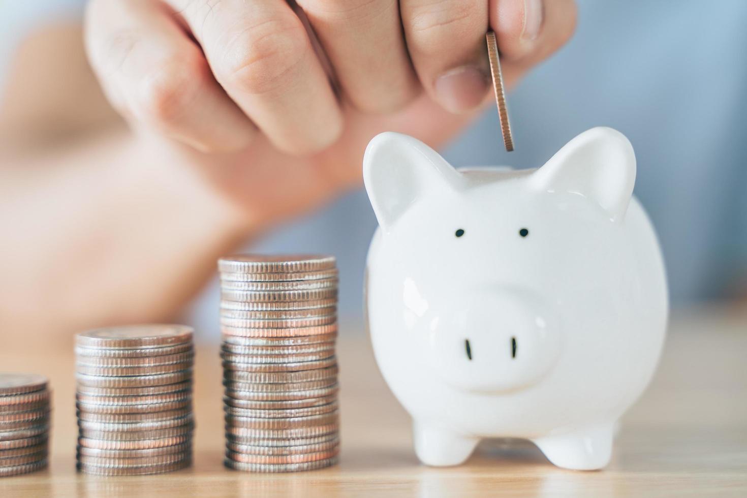 Closeup of man hand putting money coin into piggy bank for saving money. saving money and financial concept photo