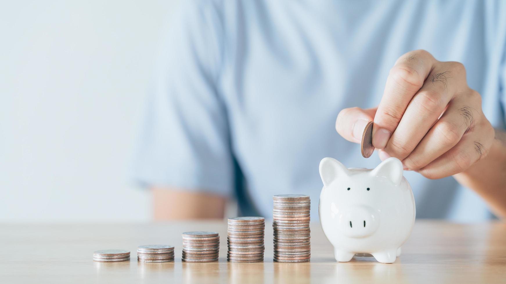 Closeup of man hand putting money coin into piggy bank for saving money. saving money and financial concept photo