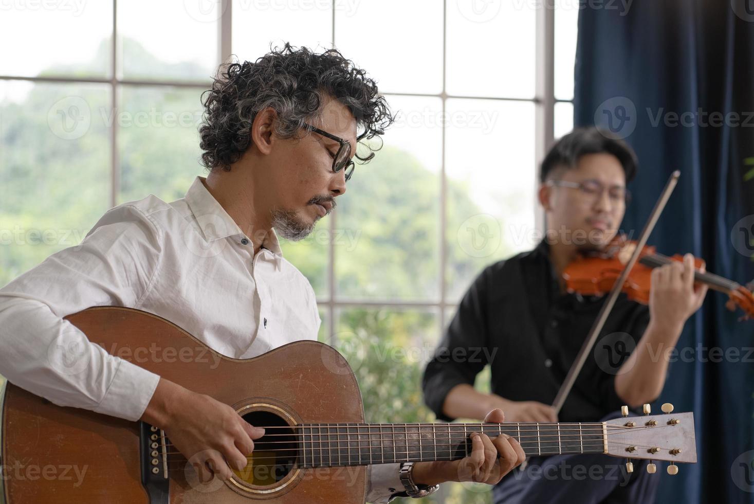 dos músicos practican tocando la guitarra y el violín juntos foto