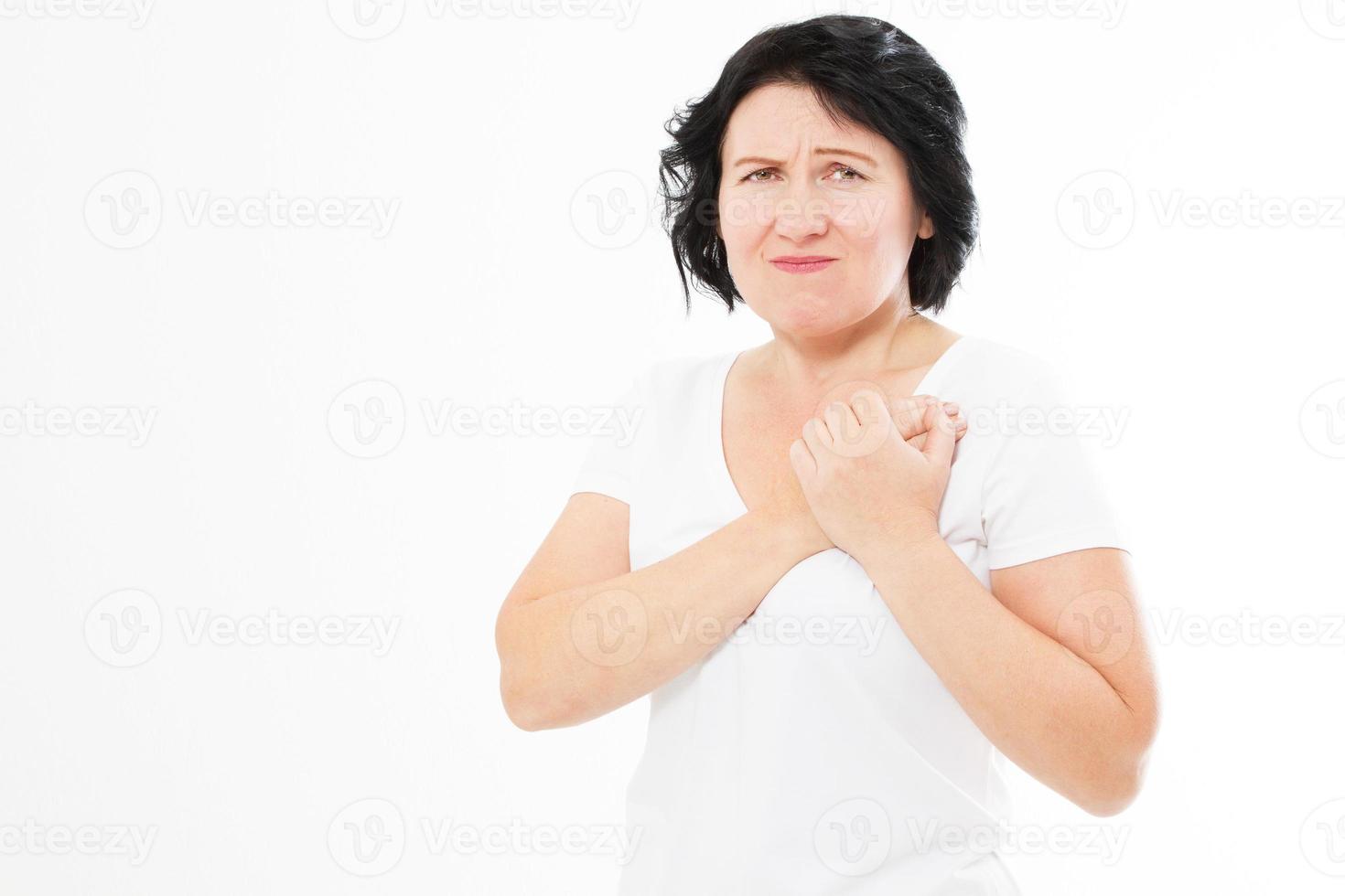 Close up of woman who has chest pain, isolated on white - middle aged woman feeling heart pain and holding her chest. photo