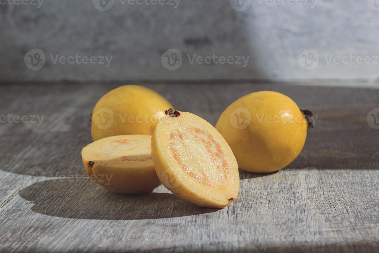 Guayaba amarilla sobre fondo de madera. vitamina c, dieta de frutas saludables. foto