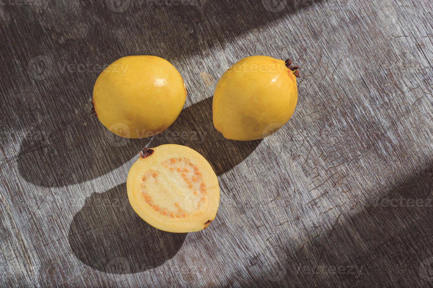 Guayaba amarilla sobre fondo de madera. vitamina c, dieta de frutas saludables. foto