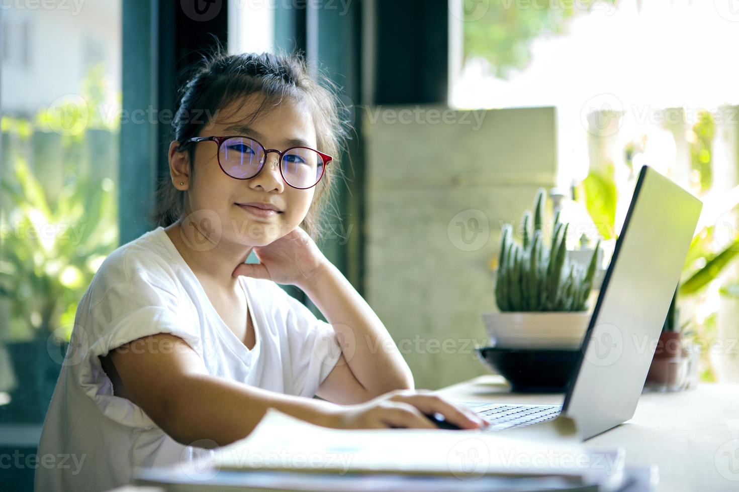 Los niños asiáticos que trabajan en la computadora portátil en casa foto