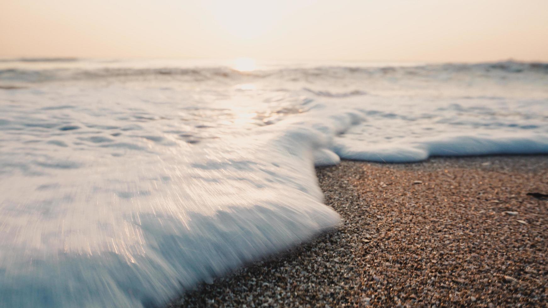 Tropical beach with wave,blue sky on golden beach sand in sunset light photo