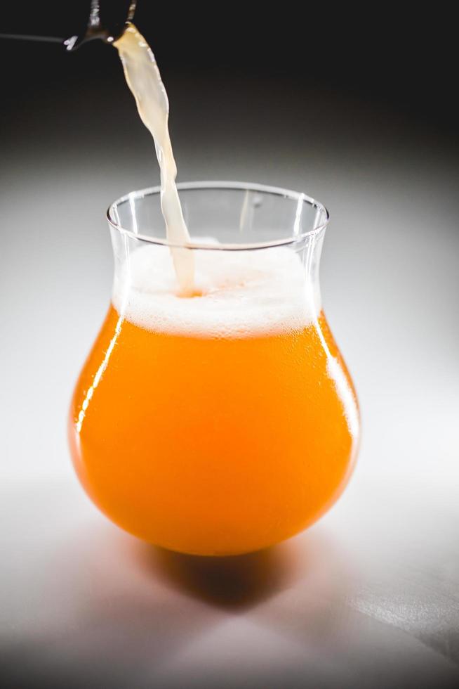 Close-up glass of homebrewed rhubarb beer with white foam. photo