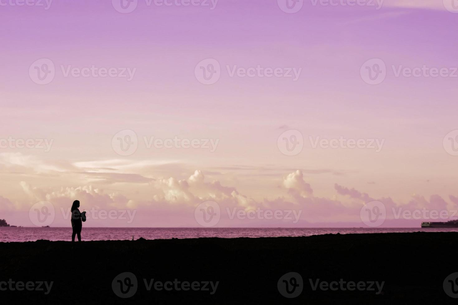 a girl alone on the beach at dusk. A girl is enjoying me time. photo