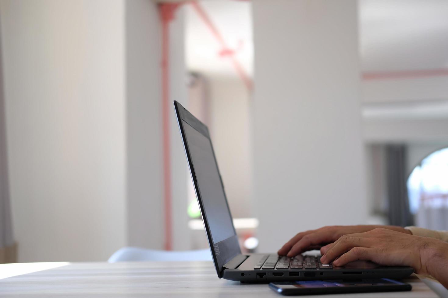 Hand typing on a laptop computer at a desk in close-up. photo