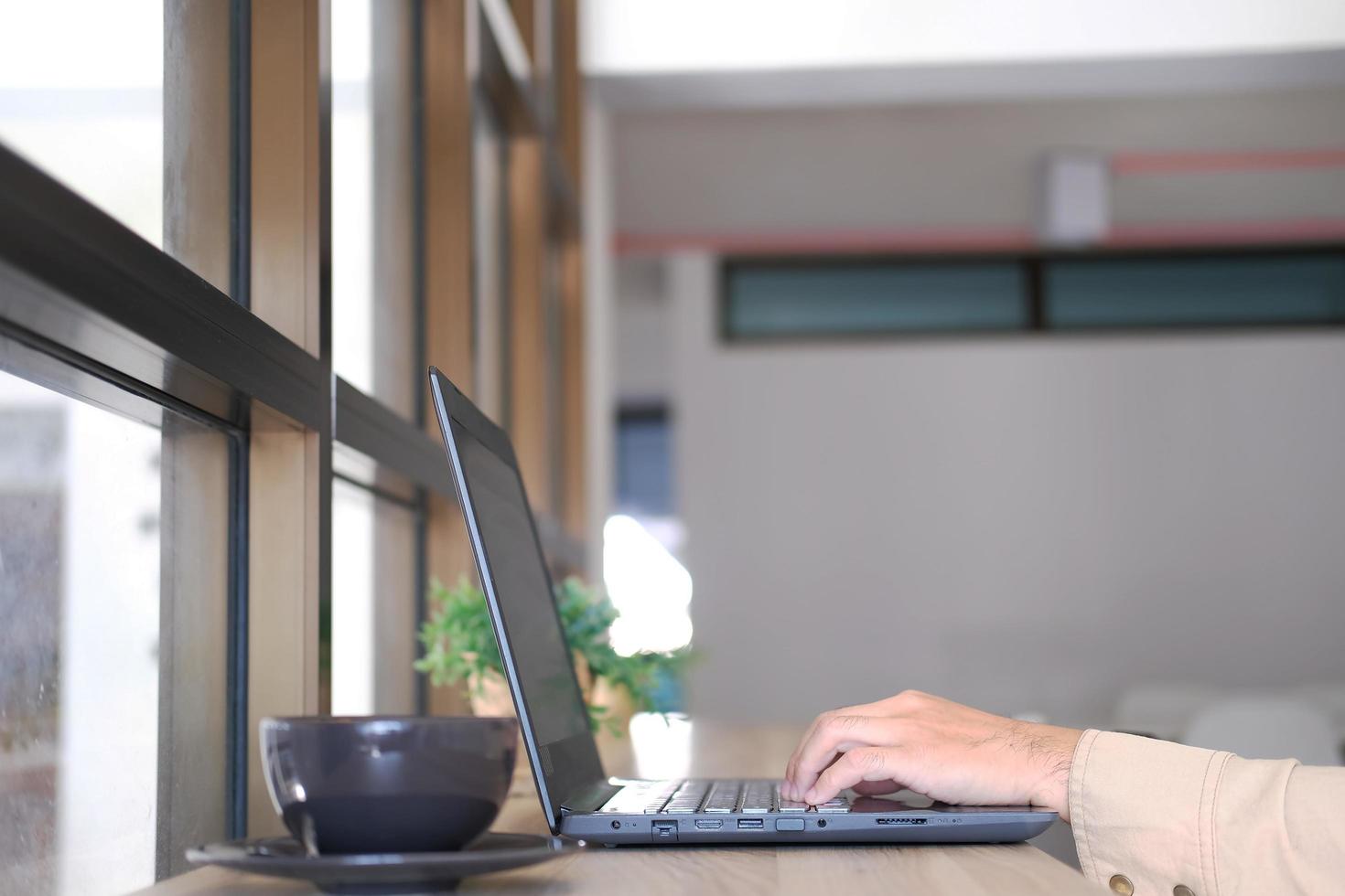 hombre que usa una computadora portátil en línea, sentado en la mesa de la oficina, mirando la pantalla de la computadora, hombre enfocado usando la banca por Internet, enviando correo electrónico y buscando información foto