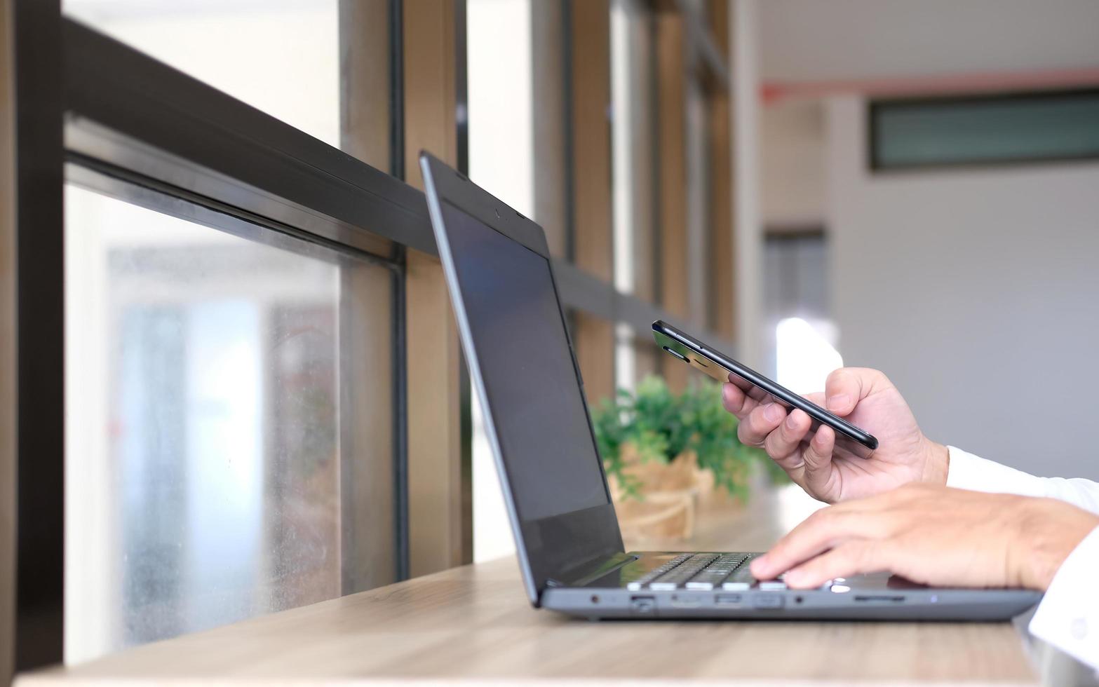 Primer plano de las manos de un hombre tomadas con un teléfono inteligente, en el café, un hombre está en su teléfono, escribiendo mensajes en las redes sociales. foto