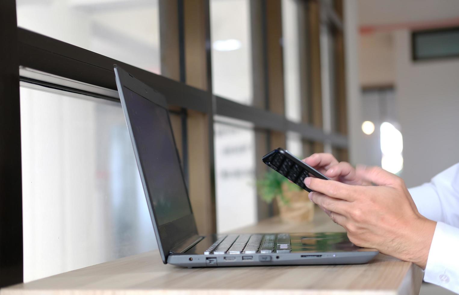 Close-up of a man's hands taken using a smartphone, At the cafe, a man is on his phone, typing messages on social media. photo