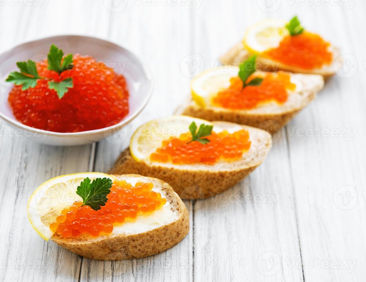 Red caviar in bowl and sandwiches photo