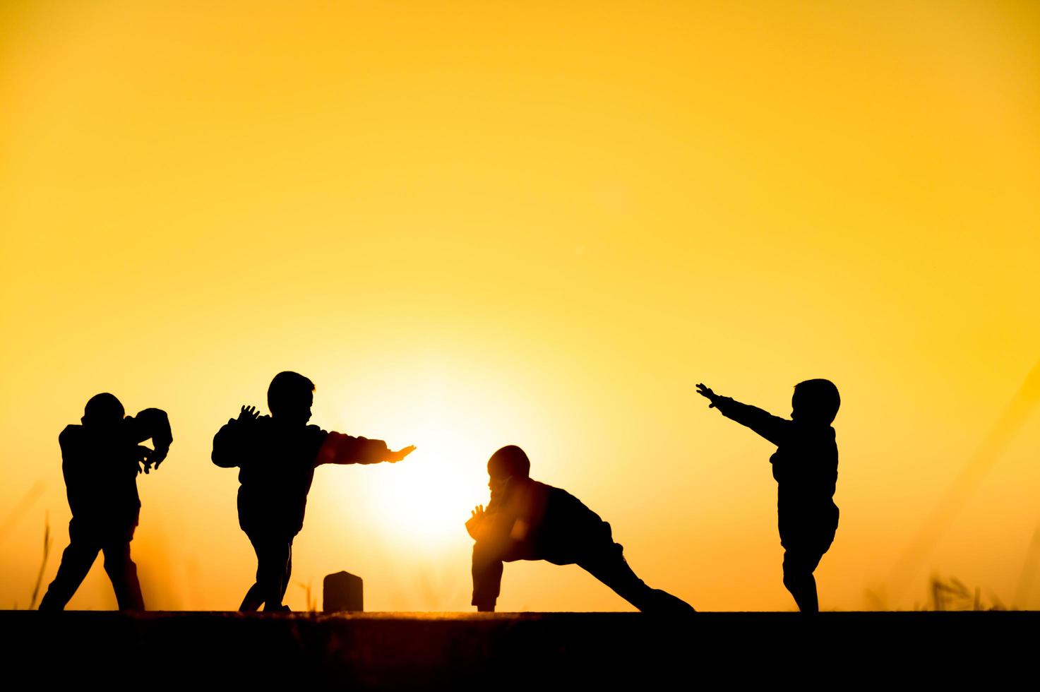 Child silhouette playing fun with many friends and playing against the sunset photo