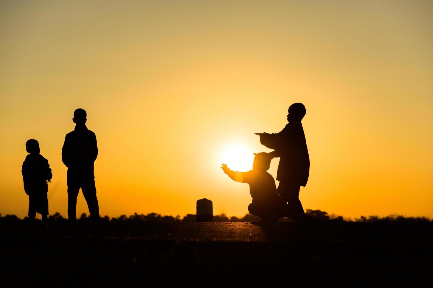 Child silhouette playing fun with many friends and playing against the sunset photo