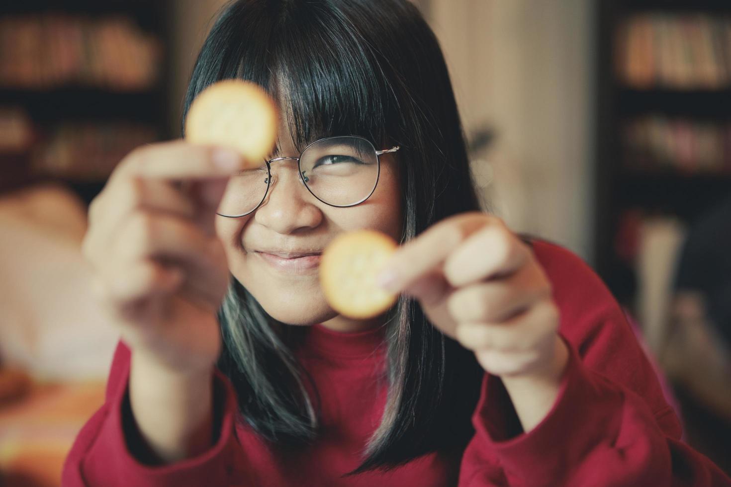 Adolescente asiático mostrar galleta de crema en el comedor de casa foto