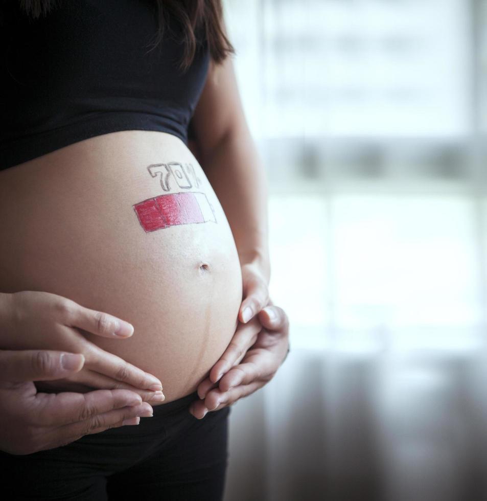 close up on pregnant belly with loading battery concept photo