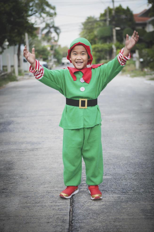 asian children wearing red and green suit of santa claus theme standing outdoor photo