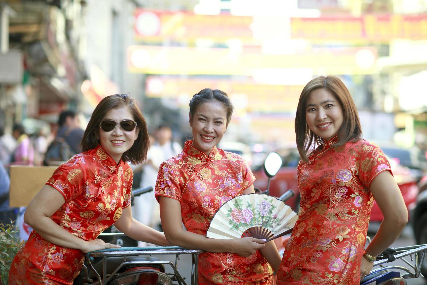 three asian woman wearing chinese tradition suit standing in bangkok china town photo