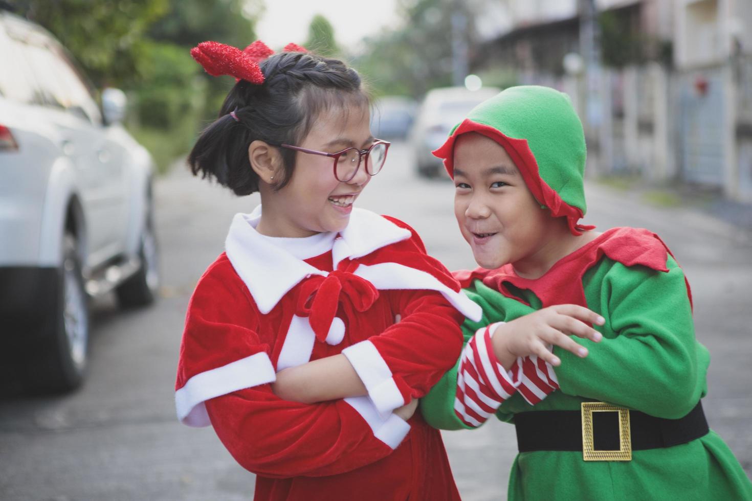 niña y niño asiático vistiendo traje de santa claus jugando con felicidad al aire libre foto