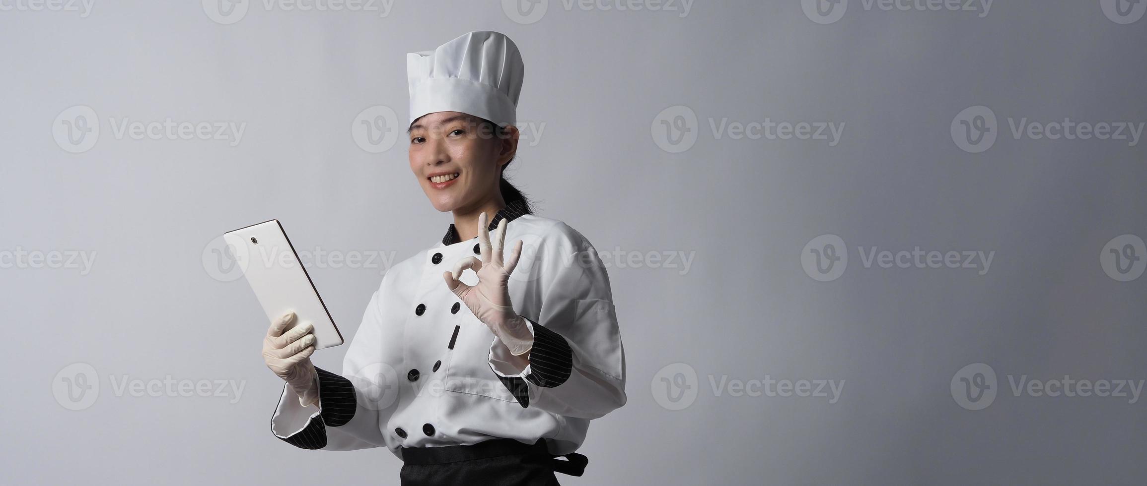 Asian woman chef holding smartphone or digital tablet and received order from online photo