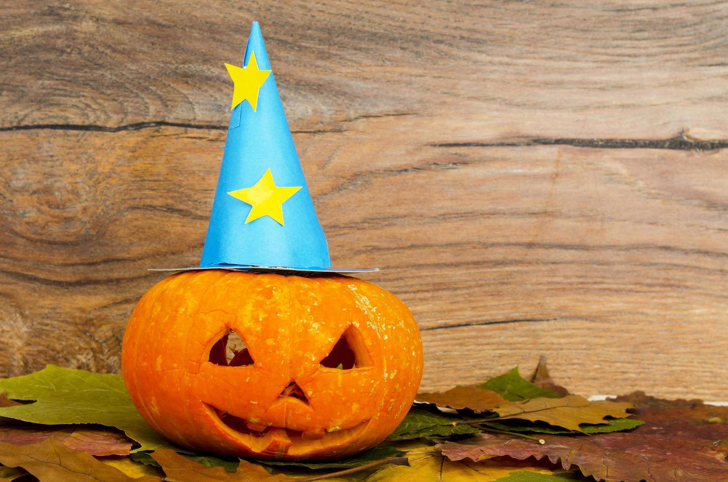 Funny orange pumpkin on background of autumn leaves for halloween photo