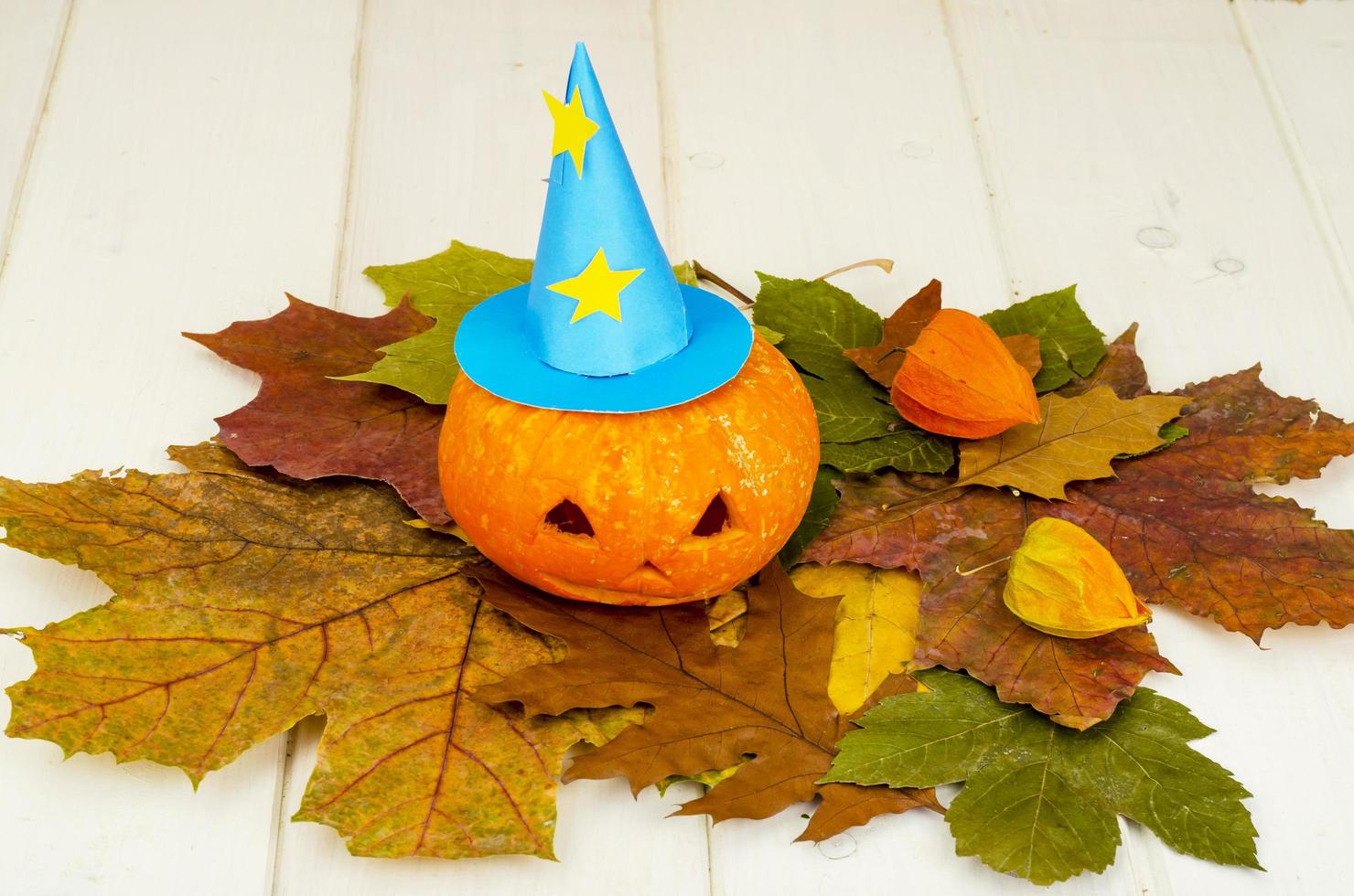 Calabaza naranja divertida sobre fondo de hojas de otoño para halloween foto