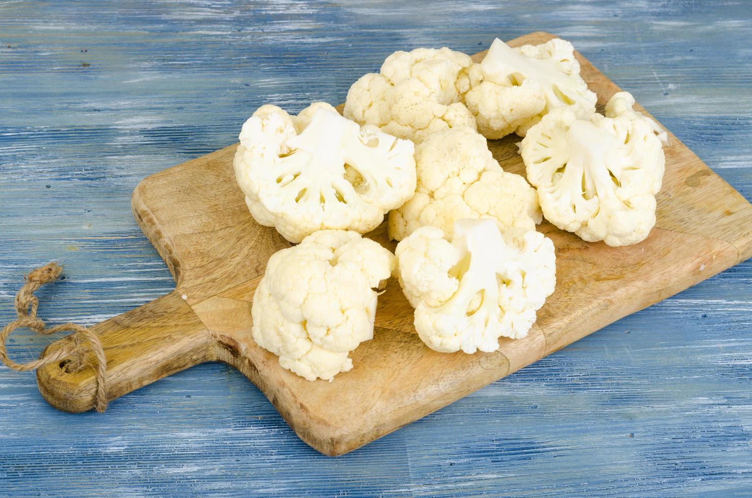 Inflorescences of fresh cauliflower on kitchen wooden board. photo