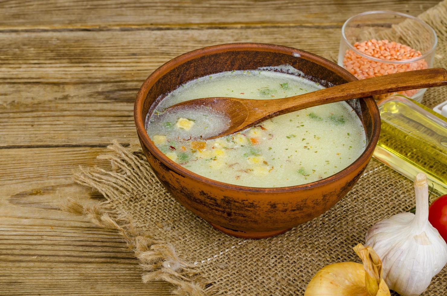 Vegetable soup with lentils in clay bowl on table photo