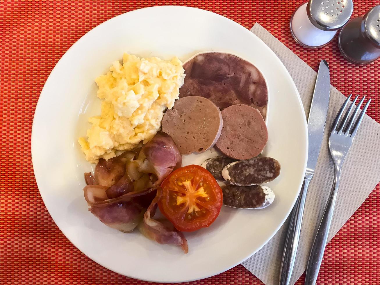 Set of dishes on breakfast table. Scrambled eggs, omelette, pate, croissants, champignons, crispy bacon, sausages. photo