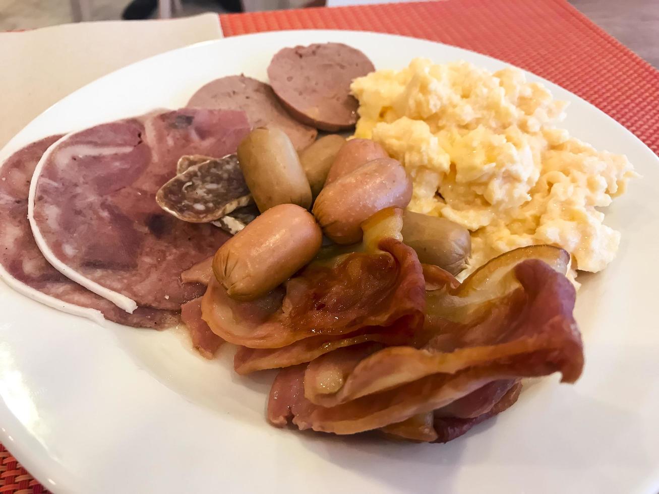 Set of dishes on breakfast table. Scrambled eggs, omelette, pate, croissants, champignons, crispy bacon, sausages. photo