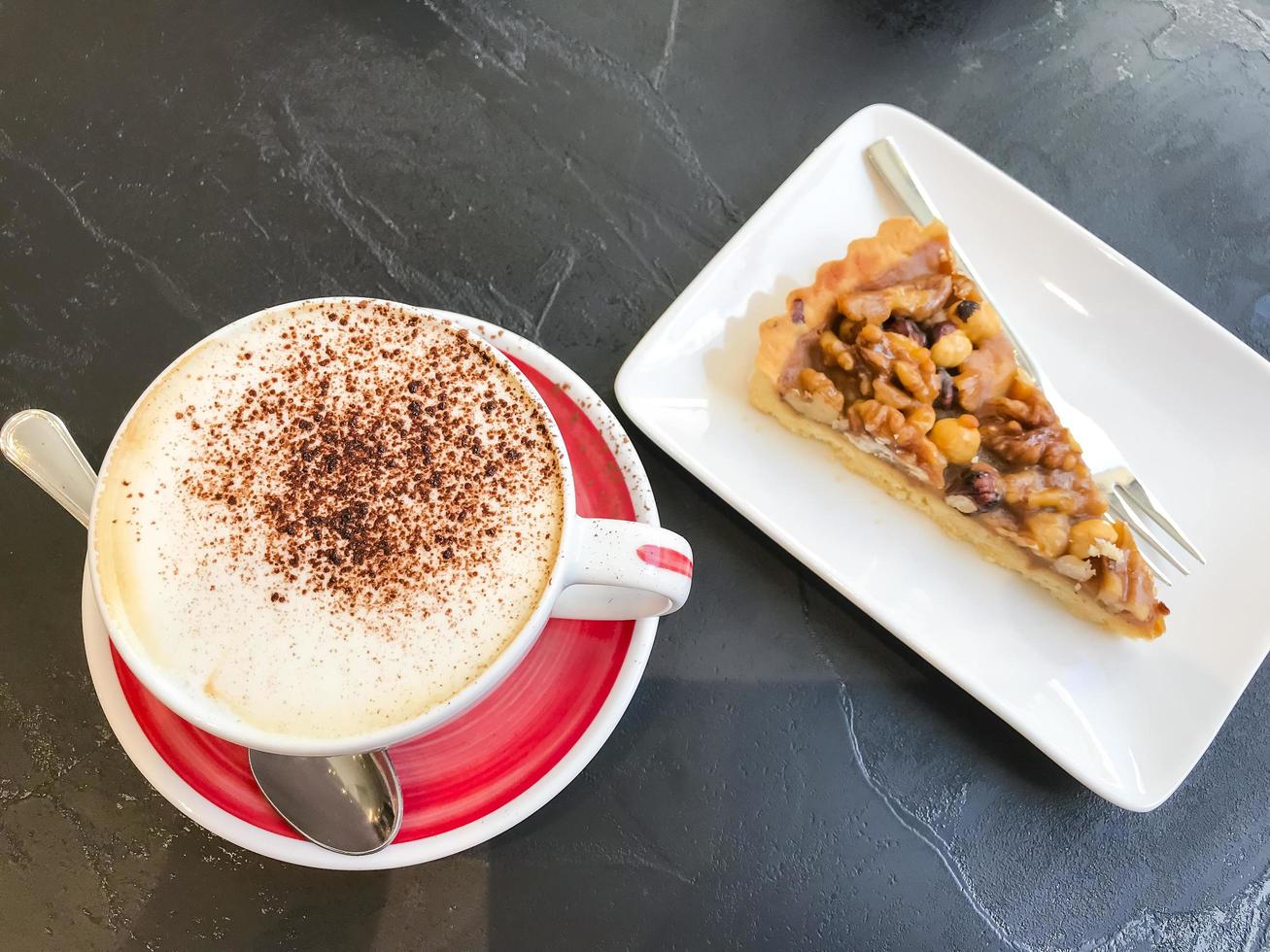 Mesa bistró de piedra negra con tazas de capuchino y bollería. foto