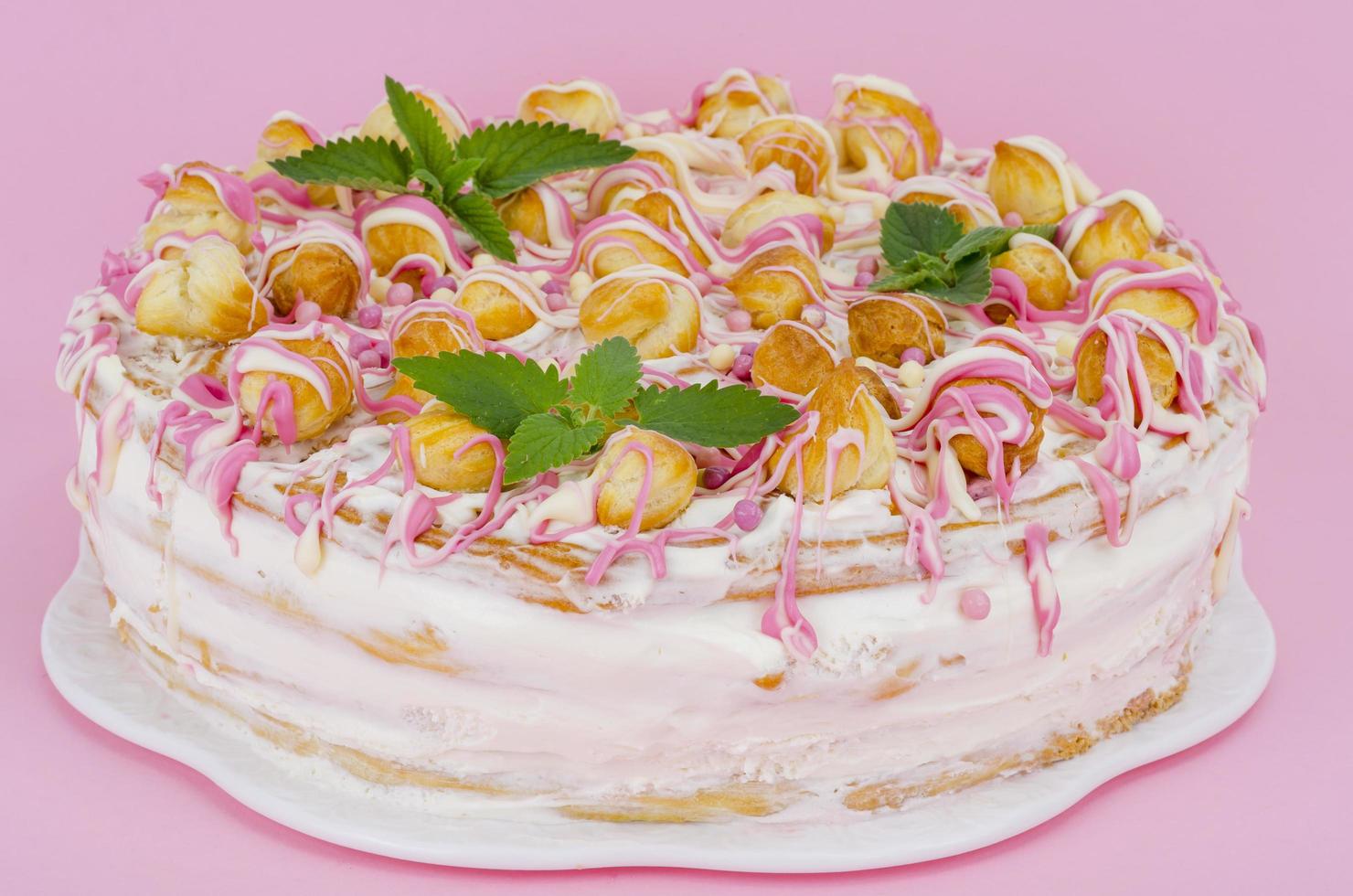 Homemade cream cake decorated with eclairs. Photo