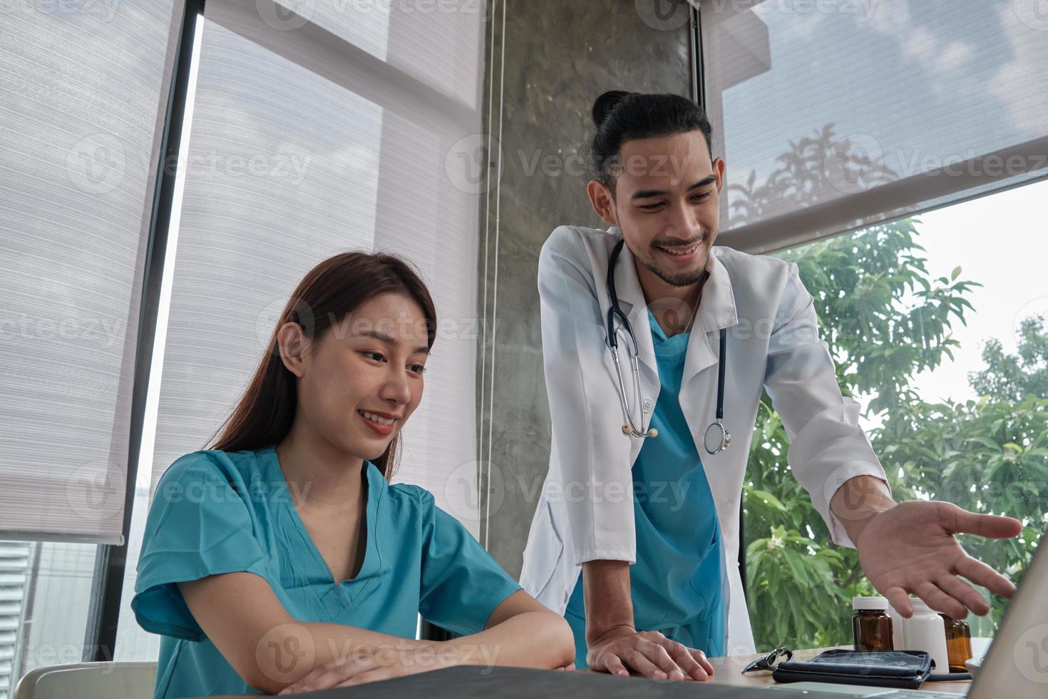 Healthcare team partners. Two uniformed young Asian ethnicity doctors are co-workers discussing medication in hospital's clinic office. Specialist persons are experts and professionals. photo