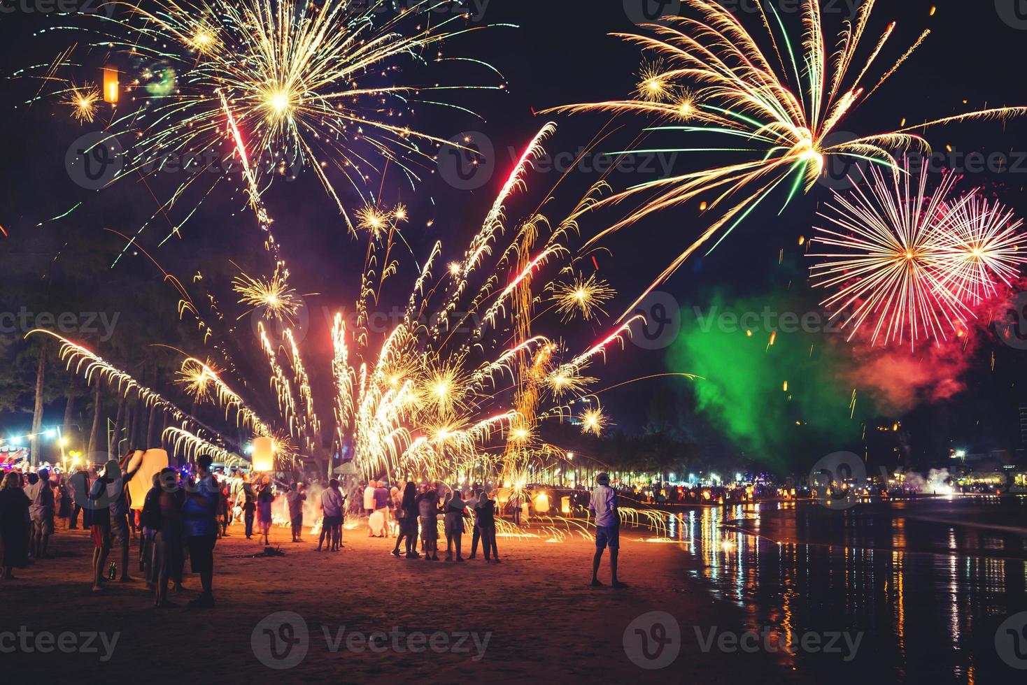 Fuegos artificiales con siluetas de personas en eventos de vacaciones.Fuegos artificiales de año nuevo en la playa. los viajeros y la gente celebran el día de año nuevo en kamala beach phuket, tailandia. foto