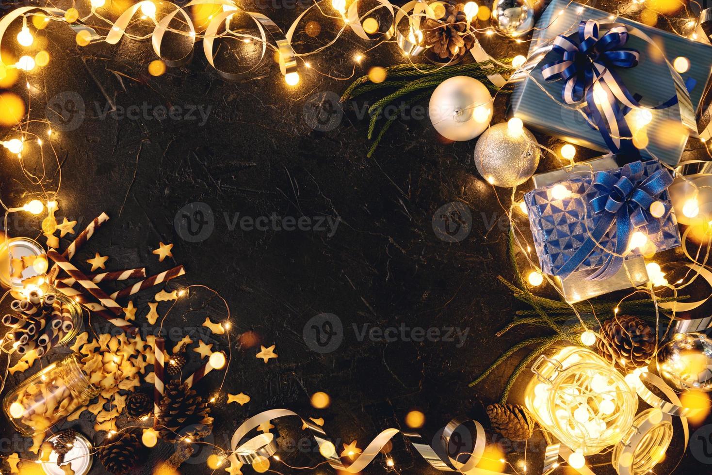 Christmas gift with blue ribbon and Christmas decoration balls on abstract bokeh black background with copy space. Holiday background greeting card for Merry Christmas and New Year. photo
